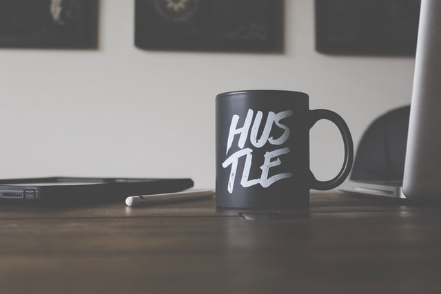 side hustle desk with coffee mug that says "hustle"